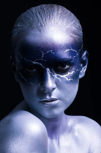 Portrait of young beautiful woman with lightning design face art on black background. Female lightning design body art. Blue silver face art.