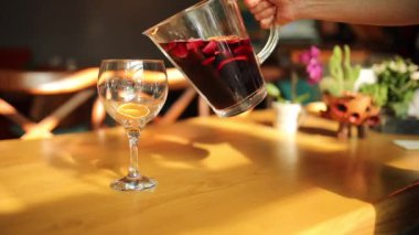 Sürahiden cama kırmızı şarap sangria kokteyldöken kadın el. 