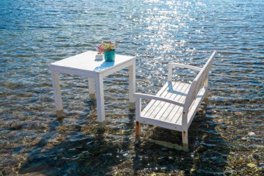 Türkiye'nin Bodrum kenti Gumusluk'ta Bodrum sahilinde balık restoranı veya kafe ve begonviller çiçeği manzarası. Güzel Ege Denizi'ne yakın Bodrum ilçesinde Ege sahil tarzı renkli sandalyeler, evler, marina, yelkenli tekneler, yatlar, masalar ve çiçekler.