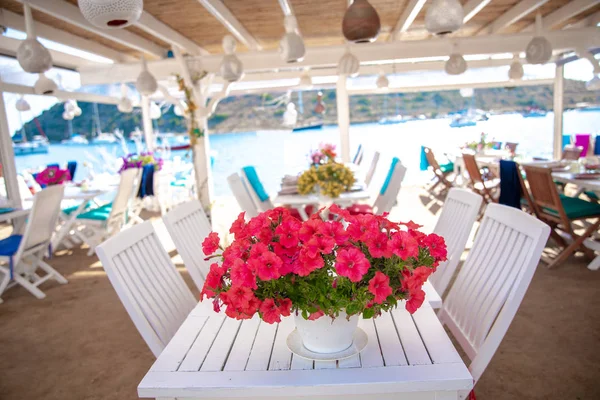 トルコのボドルム市グムスルクのボドルムビーチにある魚のレストランやカフェ ブーゲンビリアの花の眺め エーゲ海の海辺スタイルのカラフルな椅子 マリーナ セーリングボート ヨット テーブル 花美しいエーゲ海の近くのボドルムの町 — ストック写真