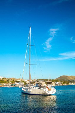 Türkiye'nin Bodrum kenti Gumusluk'ta Bodrum sahilinde balık restoranı veya kafe ve begonviller çiçeği manzarası. Güzel Ege Denizi'ne yakın Bodrum ilçesinde Ege sahil tarzı renkli sandalyeler, evler, marina, yelkenli tekneler, yatlar, masalar ve çiçekler.