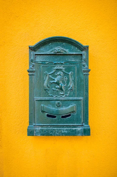 Green, old, vintage mailbox hanging on the yellow wall
