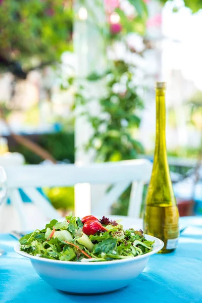 Greek, Mediterranean or Aegean Green fresh vegetarian Salad on the table in Fish Restaurant. Green Salad in bowl with olive oil at Beach Fish Restaurant in Greece or Turkey.