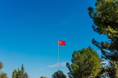 Bulutlar ve güneşile temiz mavi gökyüzüne sallanan Türk bayrağı.