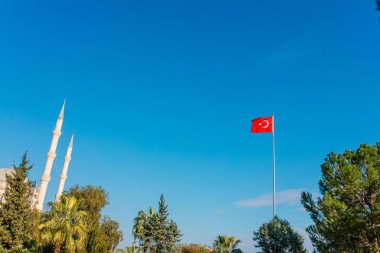 Bulutlar ve güneşile temiz mavi gökyüzüne sallanan Türk bayrağı.