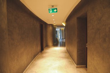 Boş otel veya ofis koridorunda Acil Çıkış işareti veya sembolü. Boş otel katında yeşil tehlike veya Kaçış işareti