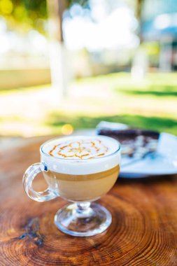 Açık havada ahşap masada latte kahve ve kek