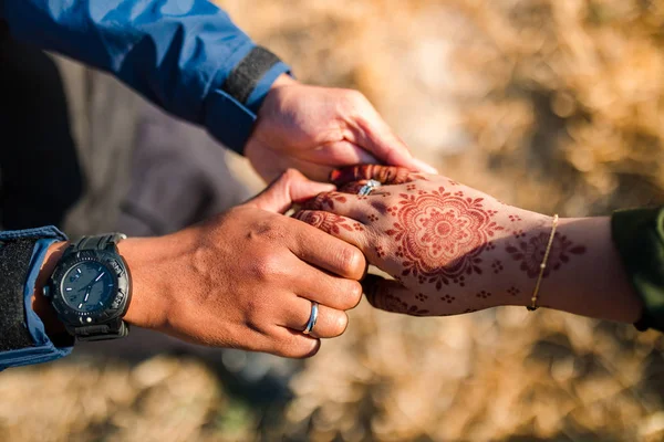 Genç ve mutlu bir çift el ele tutuşuyor. Erkek ya da erkek ve kız ellerini tutuyorlar. Kızın hanı kınalı. Asyalı çift birbirini seviyor.