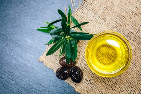 Organic, natural and healthy cold pressed olive oil on wooden table. Virgin italian or spanish olive oil in a bowl for healthy vegetarian or vegan breakfast close up concept image.