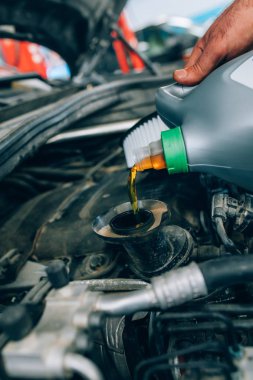 Motor bakımı sırasında garajda çalışan oto tamircisi. Oto servis garajında bir araba tamiri sırasında mekanik döken taze yağ