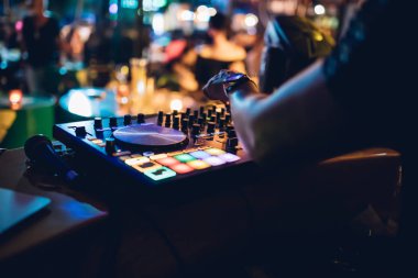 DJ, gece kulübünde canlı set ve pikabın konsolunda karışık müzik çalar. Disk Şakacı Eller kulüp partisinde ses karıştırıcı istasyonunda. Müzik çalmak ve parti yapmak için DJ karıştırıcı denetleyici paneli.