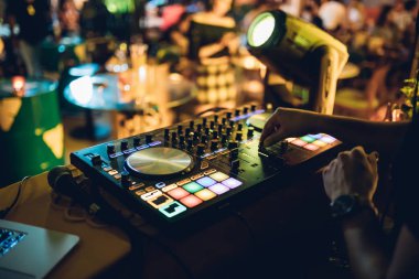 DJ, gece kulübünde canlı set ve pikabın konsolunda karışık müzik çalar. Disk Şakacı Eller kulüp partisinde ses karıştırıcı istasyonunda. Müzik çalmak ve parti yapmak için DJ karıştırıcı denetleyici paneli.