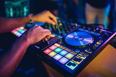 DJ, gece kulübünde canlı set ve pikabın konsolunda karışık müzik çalar. Disk Şakacı Eller kulüp partisinde ses karıştırıcı istasyonunda. Müzik çalmak ve parti yapmak için DJ karıştırıcı denetleyici paneli.