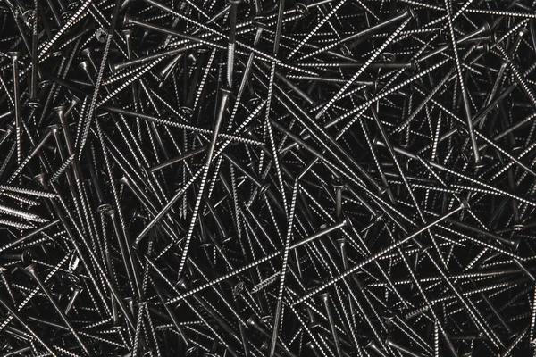 Pile of metal tapping chrome screws abstract background. Iron or metal screw nails stack industrial construction industry background.