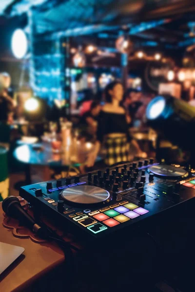 DJ plays live set and mixing music on turntable console at stage in the night club. Disc Jokey Hands on a sound mixer station at club party. DJ mixer controller panel for playing music and partying.