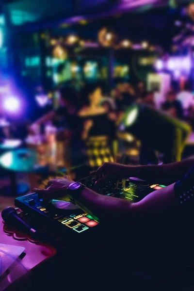 DJ plays live set and mixing music on turntable console at stage in the night club. Disc Jokey Hands on a sound mixer station at club party. DJ mixer controller panel for playing music and partying.