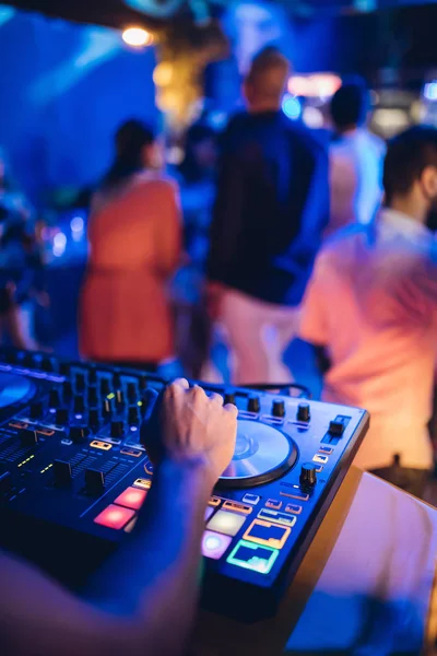 DJ plays live set and mixing music on turntable console at stage in the night club. Disc Jokey Hands on a sound mixer station at club party. DJ mixer controller panel for playing music and partying.