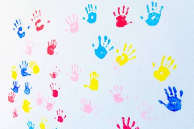 Beyaz duvar arka planda izole ellerin renkli el baskıları. Okul duvarında çocuk el izleri