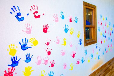 Beyaz duvar arka planda izole ellerin renkli el baskıları. Okul duvarında çocuk el izleri