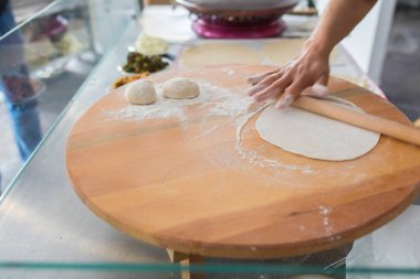 Kadın hazırlama veya borek veya ekmek hamuru yapma. Eller un ile hamur üzerinde oklava tutmak. Borek, ekmek veya ahşap bir masa arka plan üzerinde hamur pasta. Geleneksel Türk pide, pide veya yufka ekmeği.