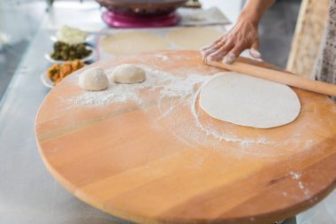 Kadın hazırlama veya borek veya ekmek hamuru yapma. Eller un ile hamur üzerinde oklava tutmak. Borek, ekmek veya ahşap bir masa arka plan üzerinde hamur pasta. Geleneksel Türk pide, pide veya yufka ekmeği.