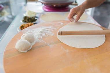 Kadın hazırlama veya borek veya ekmek hamuru yapma. Eller un ile hamur üzerinde oklava tutmak. Borek, ekmek veya ahşap bir masa arka plan üzerinde hamur pasta. Geleneksel Türk pide, pide veya yufka ekmeği.