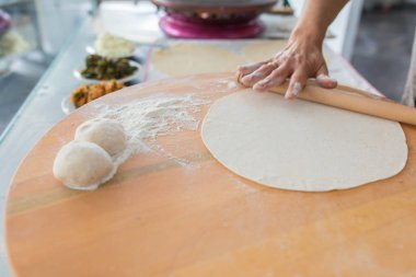 Kadın hazırlama veya borek veya ekmek hamuru yapma. Eller un ile hamur üzerinde oklava tutmak. Borek, ekmek veya ahşap bir masa arka plan üzerinde hamur pasta. Geleneksel Türk pide, pide veya yufka ekmeği.