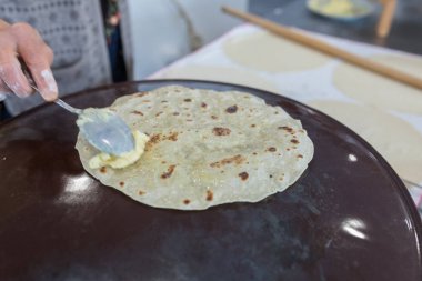 Kadın hazırlama veya borek veya ekmek hamuru yapma. Eller un ile hamur üzerinde oklava tutmak. Borek, ekmek veya ahşap bir masa arka plan üzerinde hamur pasta. Geleneksel Türk pide, pide veya yufka ekmeği.