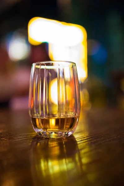 Single glass of whisky or whiskey on wooden table at pub, bar or restaurant at night. Scotch, bourbon or irish whiskey on wooden table. Nightlife concept image