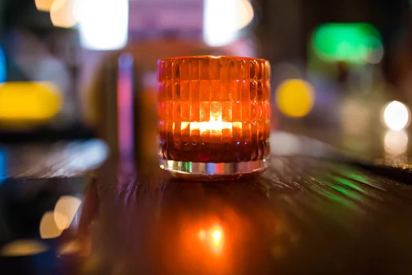 Decorative Orange or red candle light in glass on wooden table at night in cafe or restaurant background interior