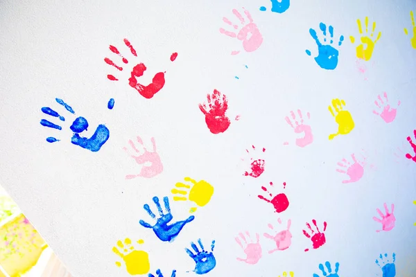 Colorful hand prints of hands isolated on white wall background. Children\'s handprints on school wall