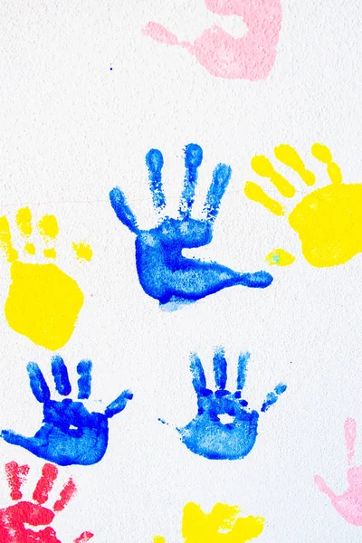Colorful hand prints of hands isolated on white wall background. Children\'s handprints on school wall