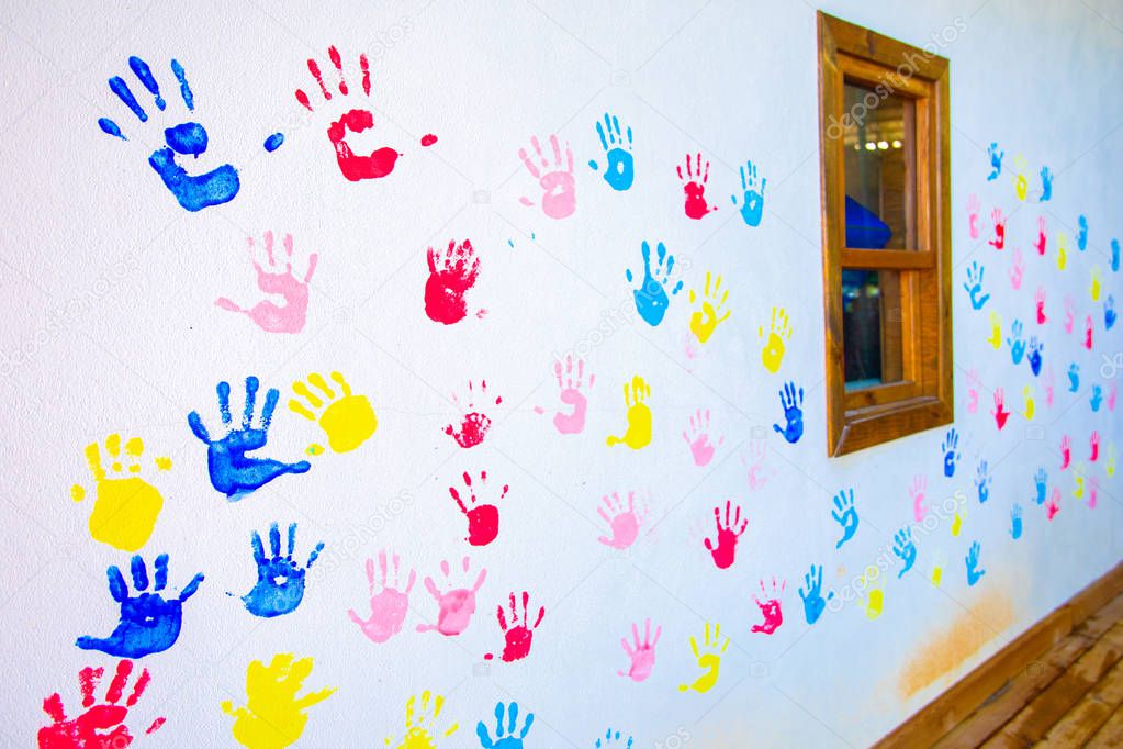 Colorful hand prints of hands isolated on white wall background. Children's handprints on school wall
