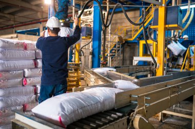 Modern fabrikada büyük depoda satır veya beyaz çuval torba yığınları işçi yükleme. Fabrika veya depoda paketleme