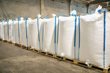 Modern fabrikada büyük depoda satır veya beyaz çuval torba yığınları. Fabrika veya depoda paketleme