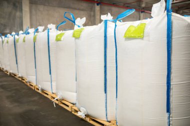 Modern fabrikada büyük depoda satır veya beyaz çuval torba yığınları. Fabrika veya depoda paketleme