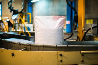 Modern fabrika makine bandında beyaz çuval torbası. Fabrika veya depoda paketleme