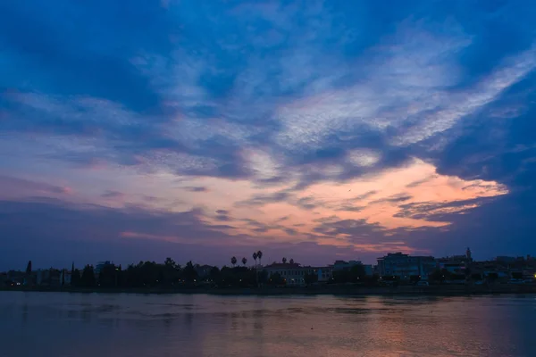 Colorful pastel pink and red clouds with Blue sky abstract background and River. Clouds and city silhouette at sunset.