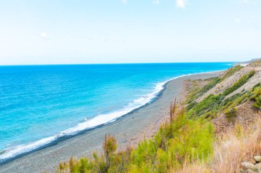 Türkiye 'nin Bodrum plajında Akdeniz ya da Ege kıyıları, kıyı ya da körfez kıyıları kaya ve dalgalarla kaplı. Mavi deniz, okyanus ve ağaçlarla dolu yaz günü manzarası. Türkiye 'de tatil ve tatil.