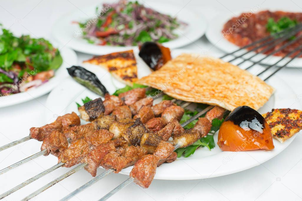 Traditional Turkish Adana Shish Kebap with salads and appetizers. Selective Focus Turkish Cuisine Dining Dinner Table. This is Turkish food culture in Turkish Restaurant.