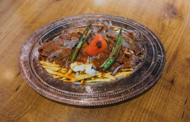 Geleneksel Türk Donör Kebabı İskender olarak da bilinir. Türk tarzı kebap yapan kebap ahşap masa arkasında.