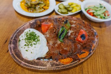 Geleneksel Türk Donör Kebabı İskender olarak da bilinir. Türk tarzı kebap yapan kebap ahşap masa arkasında.