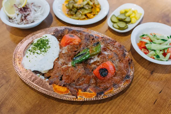 Geleneksel Türk Donör Kebabı İskender olarak da bilinir. Türk tarzı kebap yapan kebap ahşap masa arkasında.