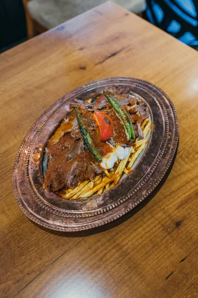 Geleneksel Türk Donör Kebabı İskender olarak da bilinir. Türk tarzı kebap yapan kebap ahşap masa arkasında.