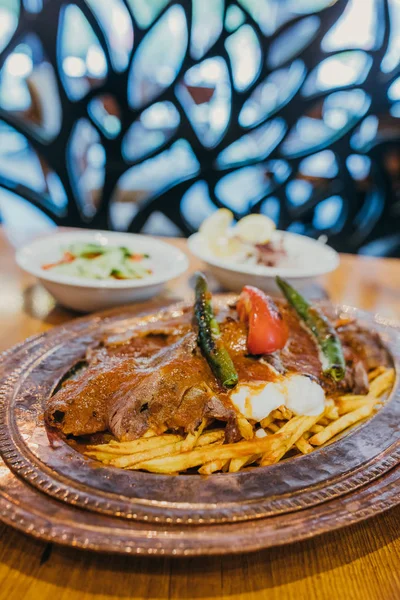 Geleneksel Türk Donör Kebabı İskender olarak da bilinir. Türk tarzı kebap yapan kebap ahşap masa arkasında.