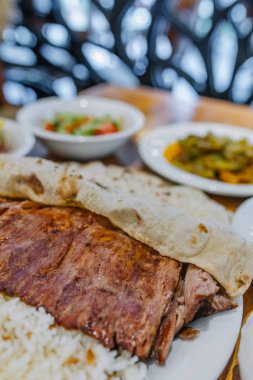 Geleneksel Türk Donör Kebabı İskender, shawarma veya gyros olarak da bilinir. Türk tarzı kebapçı Türk Restoranı 'nda ahşap masa arkasında kebap yapıyor