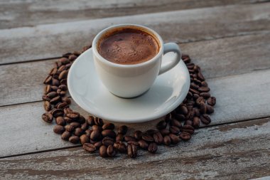 Beyaz ahşap masada kahve çekirdekleri dökülmüş Türk ya da Yunan kahvesi. Bu Yunan ya da Türk mutfağından geleneksel lezzetli Yunan ya da Türk kahvesi.