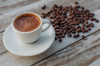 Beyaz ahşap masada kahve çekirdekleri dökülmüş Türk ya da Yunan kahvesi. Bu Yunan ya da Türk mutfağından geleneksel lezzetli Yunan ya da Türk kahvesi.