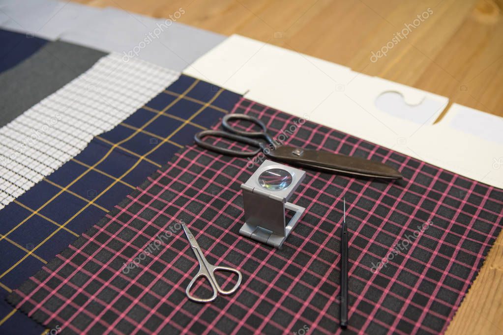 Textile fabric pattern sample with magnifier and scissors. Textile industry concept background image.