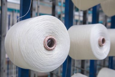 Tekstil değirmenindeki büküm makinesinin üzerindeki bir grup bobbin ipliği. Tekstil fabrikasında iplik topu yapmak. Tekstil endüstrisi - Tekstil fabrikasında dönen makinenin iplik makaraları